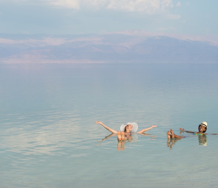 Lovely girls floating in salty water of Dead Sea and with Arms outstretched . Unusual buoyancy caused by high salinity.